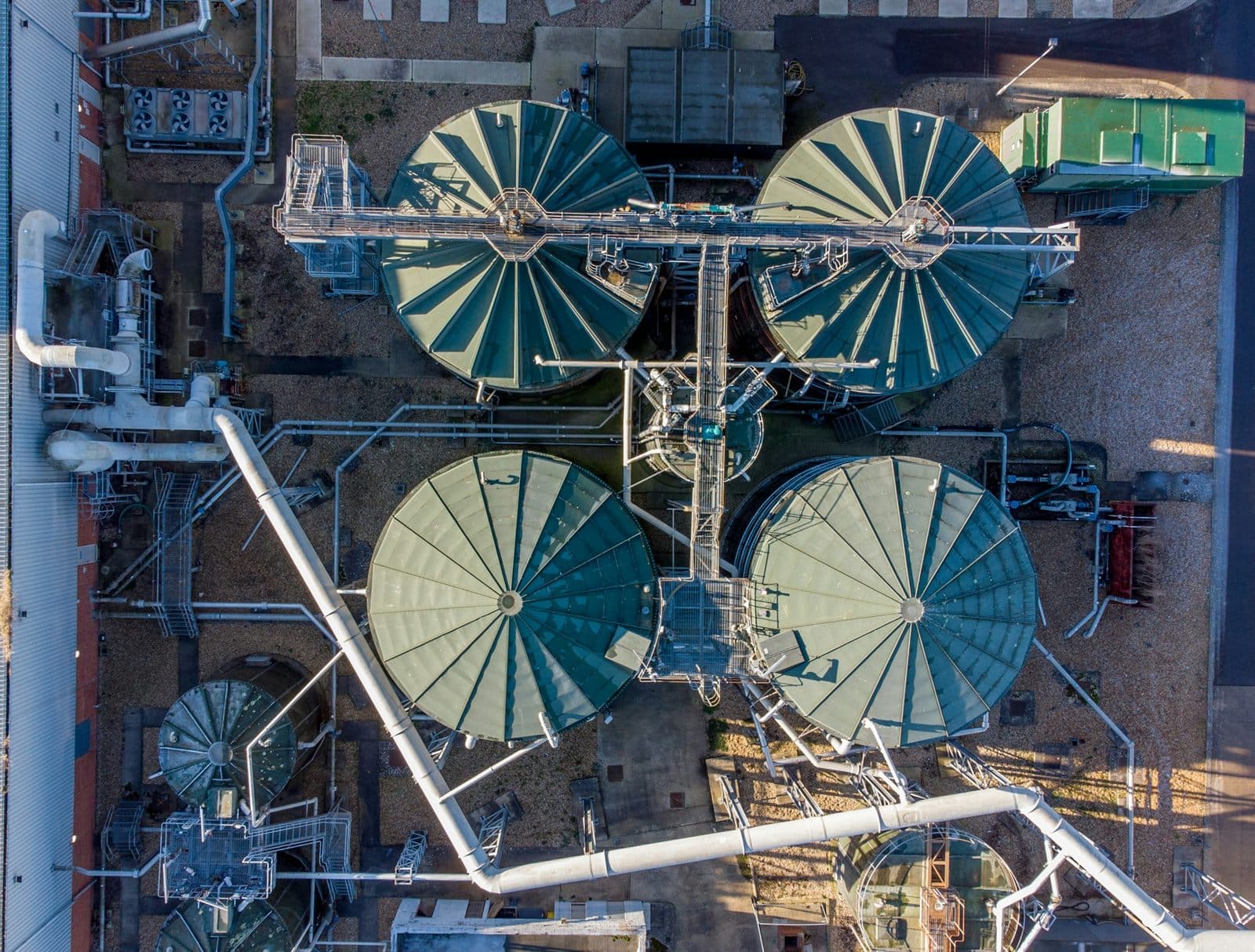 Aerial view of an industrial tank farm — large circular storage tanks linked by pipework and walkways